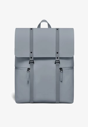 Lichtgrijze rugzak met bovenklep, twee verticale riemen met gespen, twee zijvakken met ritsen en een draaghendel bovenop.