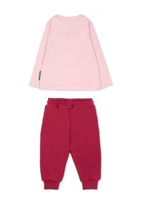 Chemise rose à manches longues avec un col rond et une étiquette, associée à un pantalon de survêtement rouge avec une taille élastique et des chevilles resserrées.