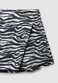 Tessuto nero con una stampa zebratica testurizzata in bianco e beige, caratterizzato da un bordo ripiegato e una finitura liscia.