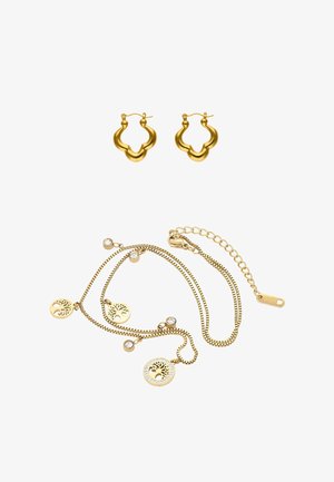 Arany karika fülbevalók hullámos mintával, arany lánc nyaklánccal párosítva, amely kivágott kör alakú medálokat és apró kristály díszítéseket tartalmaz.