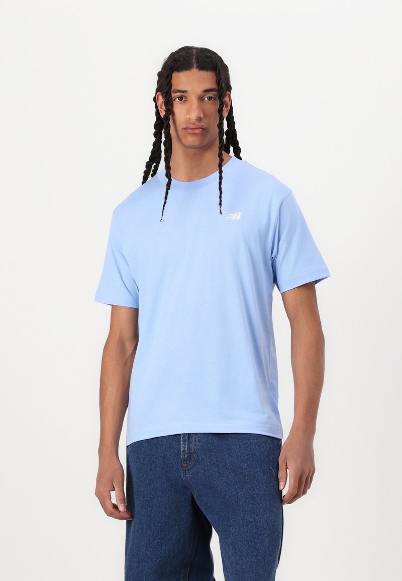 T-shirt en coton bleu clair à manches courtes et col rond. Présente un petit logo blanc sur la poitrine gauche. Alliée à un jean en denim foncé.