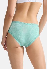 Culotte haute en vert menthe avec un motif texturé subtil et une finition décorative à bord festonné le long de la taille. Matériau doux et extensible.
