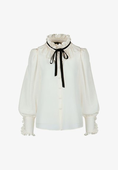 Blusa bianca con colletto e polsini arricciati, caratterizzata da un nastro nero da annodare. Tessuto morbido e liscio, con chiusura a bottoni lungo la parte frontale.
