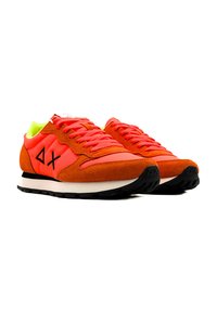Zapatillas naranjas con una combinación de ante y tela, suela negra, cordones rosas y acentos fluorescentes verdes en el cuello y el forro.