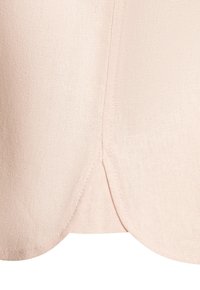 Light pink linen fabric with a soft texture; features a curved hem and visible stitching details along the seams.