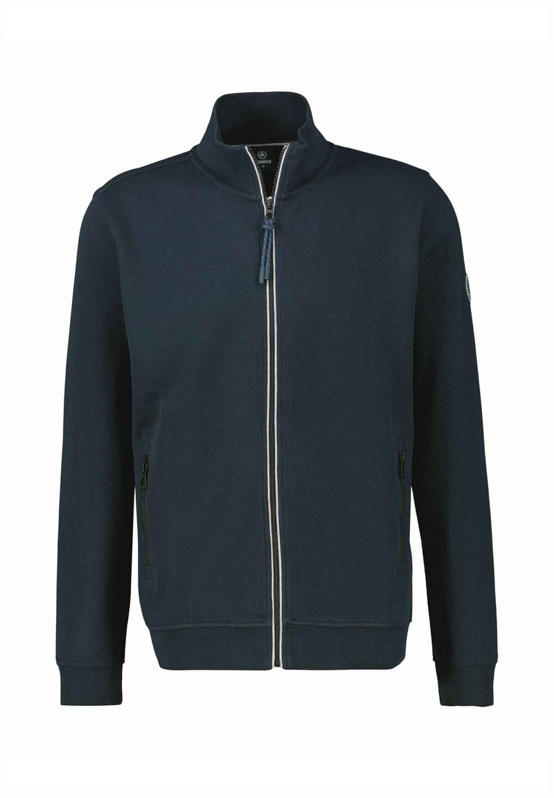 Marinekleurige ritsjack met hoge kraag, twee zijzakken en een witte streep langs de rits; ribgebreide manchetten en zoom. Getextureerde stof.