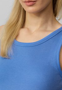 Lichtblauw geribbeld tanktop met een ronde halslijn en smalle bandjes, met een zachte textuur en een gladde afwerking.