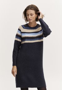Robe pull en tricot avec un col rond, une base marine et des bandes imprimées en crème, bleu et marron sur la poitrine et les manches.