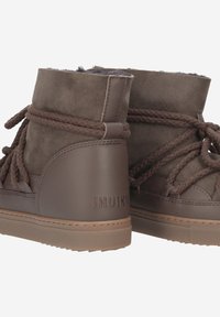 Bottines en daim marron avec une tige texturée, des lacets en corde épaisse et une semelle en caoutchouc. Présente un logo à l'arrière et une doublure douce.