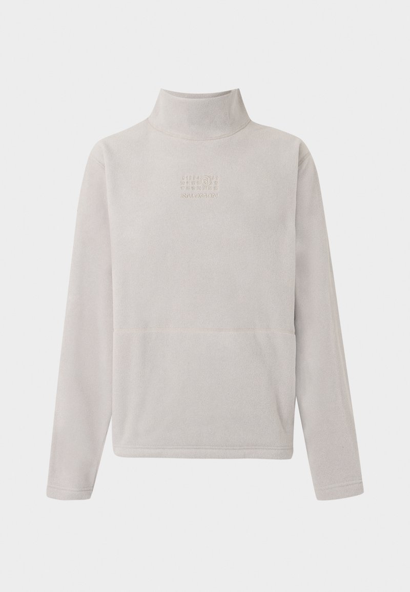 Sudadera de forro polar gris claro con cuello alto, presenta un bolsillo frontal y el logotipo "SALOMON" en relieve. Textura suave, corte relajado.