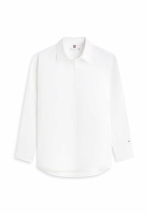 Camisa blanca de manga larga con botones, cuello, logo bordado sutil en el pecho y pequeño logo de bandera en el puño izquierdo.