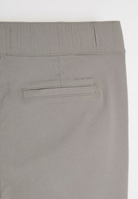Szare spodnie wykonane z teksturowanej tkaniny, z płaskim pasem w talii, jedną tylną kieszenią i minimalnymi detalami w szwie.