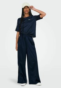 Navy Sportoutfit mit einem lockeren kurzärmeligen Oberteil und weitem Hosenbein, ausgestattet mit weißen Streifen und einem bequemen elastischen Bund.