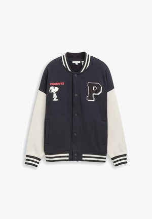 Marineblaue und weiße Collegejacke mit gestreiften Bündchen und Kragen, Peanuts Comicfigur Snoopy auf der linken Brust, roter "PEANUTS" Text und schwarzer Buchstaben "P" Aufnäher auf der rechten Seite.