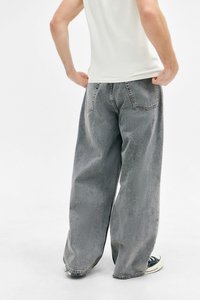 Bredde grå denim jeans med en falmet vask, to baglommer og en frynset kant. Samlet med sorte og hvide sneakers.