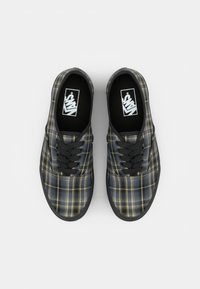 Black and yellow plaid sneakers with a canvas upper, black laces, and a rubber sole; inside features a white logo on a black insole.