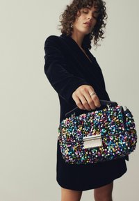 Pärlad handväska i svart bas, prydd med färgglada cirkulära paljetter, rektangulär metallklämma och en strukturerad form.