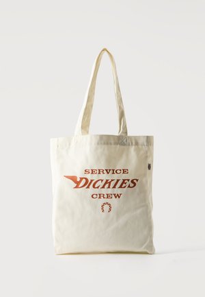 Bolsa tote beige con asas largas y texto en naranja oscuro "SERVICE DICKIES CREW" con un gráfico de ala y herradura.