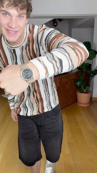 Käekell tume ümmargune nägu, kuldne metallriba; kantud mitmevärvilise mustriga pika varrukaga särgi ja mustade lühikeste pükste juurde. Siseõhkkond.