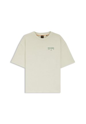 T-shirt a maniche corte color beige chiaro con scollo rotondo e piccolo testo verde "RIO DE JANEIRO" sul lato sinistro superiore del petto.