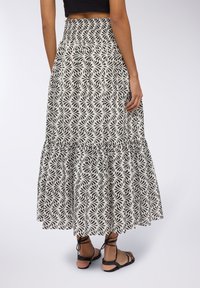 Gonna a stampa foglia in bianco e nero con vita arricciata e orlo a strati, realizzata in tessuto leggero, caratterizzata da una vestibilità fluida e rilassata.