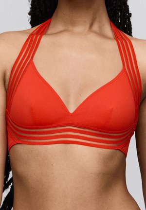 Vrouw draagt een rood halter-bikinitopje met meerdere dunne bandjes over de schouders en rondom de onderborst.