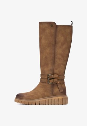 Botas marrones hasta la rodilla con un acabado de imitación de cuero suave, correas decorativas con hebillas y una suela de goma texturizada con surcos profundos.