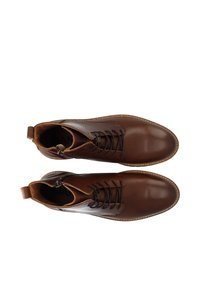 Stivali ankle in pelle marrone con una texture liscia, dotati di lacci, cerniera laterale e suola beige a contrasto.