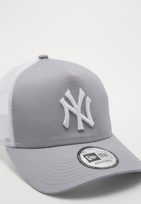 Grau Baseballcap mit einem weißen Netzrücken, ausgestattet mit einem gestickten weißen NY-Logo. Verstellbarer Riemen und gebogener Schirm.
