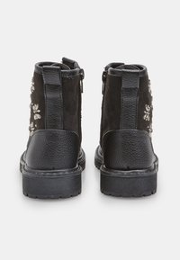 Stivaletti neri fino alla caviglia con una combinazione di suede e pelle texturizzata. Decorazioni floreali e zip laterali per una facile vestibilità. Suola in gomma spessa.
