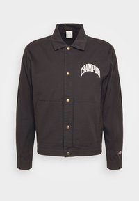 Czarna kurtka z płótna z napami, z logo "CHAMPION" w białym kolorze na lewej piersi oraz dwoma przednimi kieszeniami.