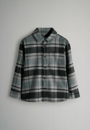 Flanellist särk musta, halli ja valge ruudulise mustriga, nööpidega ees, täispikkade varrukatega ja ühe rinnataskuga.