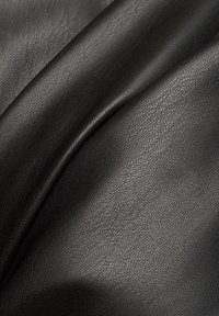 Tissu en cuir noir, texturé avec un grain fin et une légère brillance, drapé en plis doux, mettant en valeur sa flexibilité et sa surface lisse.
