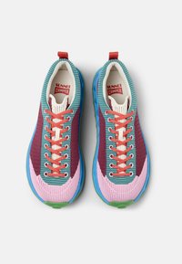 Multicolored sneakers with a knit upper in teal, maroon, and pink. Features blue soles, red laces, and a white interior. Notable striped design.