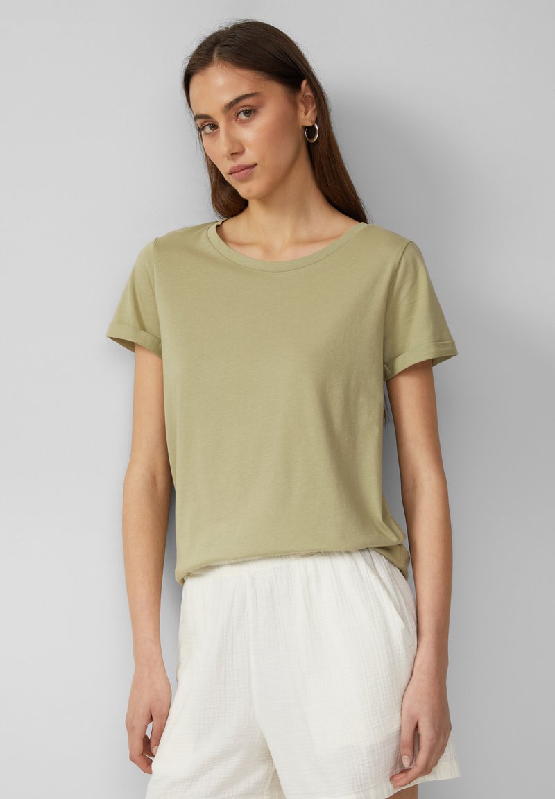 Olijfgroen katoenen t-shirt met korte mouwen en een ronde halslijn, gedragen met lichtgekleurde, gestructureerde shorts. Gladde stof, casual pasvorm.