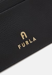 Black textured leather wallet featuring a gold "FURLA" logo. The design includes smooth stitching and a clean, minimalist layout.