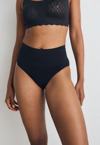 High-waisted, black underwear made of soft, stretchy fabric. Features a smooth waistband and minimalistic design without visible seams.