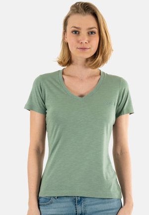 T-shirt vert en V, fabriqué en tissu doux et léger. Manches courtes avec une coupe ajustée. Logo "Guess" en surpiqûre ton sur ton.