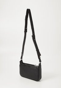 Borsa a tracolla nera realizzata in materiale testurizzato con tracolla regolabile. Presenta una chiusura con zip e un design piatto con sottili dettagli di cucitura.