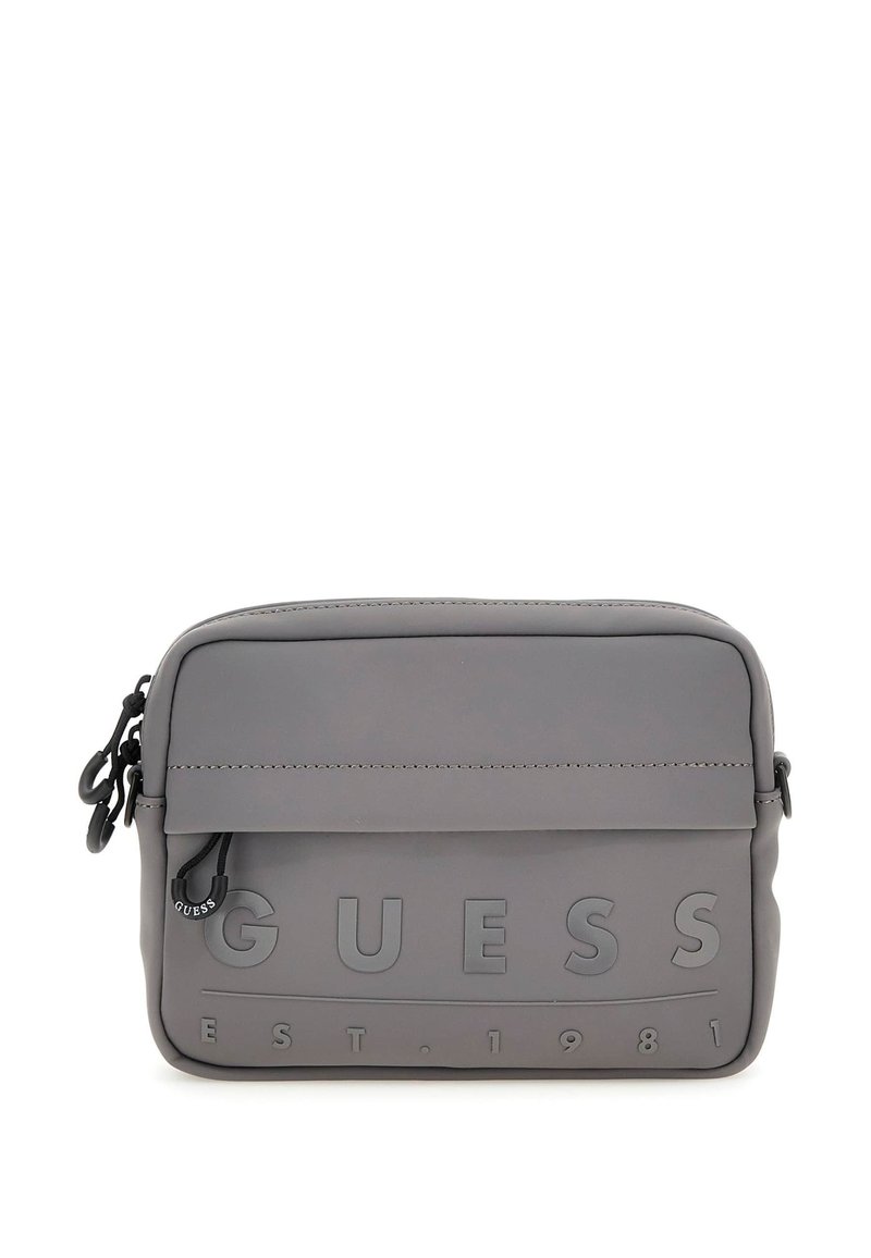 Bolso bandolera sintético gris con logo grabado de "GUESS" y "EST. 1981." Diseño sencillo con cierre de cremallera y correa ajustable.