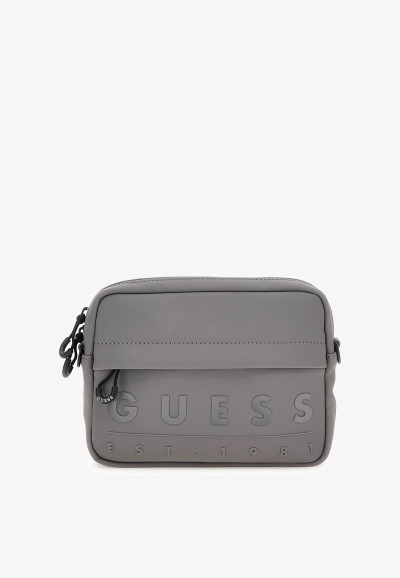 Bolso bandolera sintético gris con logo grabado de "GUESS" y "EST. 1981." Diseño sencillo con cierre de cremallera y correa ajustable.