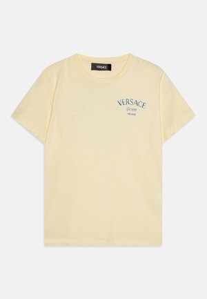 Camiseta de algodón amarilla con cuello redondo, mangas cortas y logotipo bordado en azul claro "VERSACE" en el pecho. Textura suave y ligera.