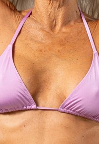 Roze driehoekige bikini-top met dunne bandjes, met geplooide stof en een gladde textuur. Toont de huidtint en het nekgebied.
