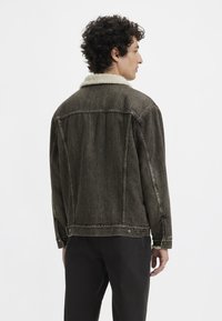 Denim jacket with a dark wash, shearling collar, long sleeves, and button details. Textured fabric with a relaxed fit.