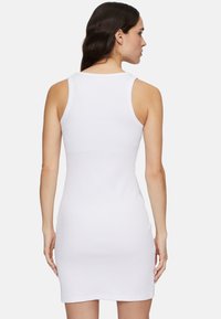Weißes geripptes ärmelloses Kleid mit taillierter Passform, rundem Halsausschnitt und kurzem Saum, das einen glatten, strukturierten Stoff hervorhebt.