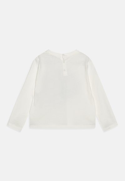 Maglietta a maniche lunghe con collo rotondo in cotone color avorio. Presenta una chiusura a bottone sul retro e una texture morbida e liscia. Design semplice e minimale.