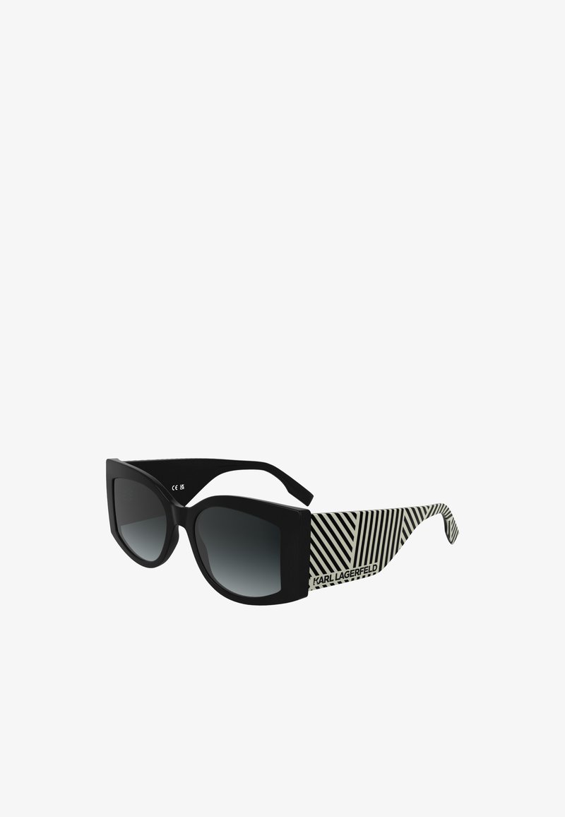 Sorte solbriller med en bred, vinklet ramme og gradientlinser. Stengene har et sort og hvitt stripete mønster med "KARL LAGERFELD"-merking.