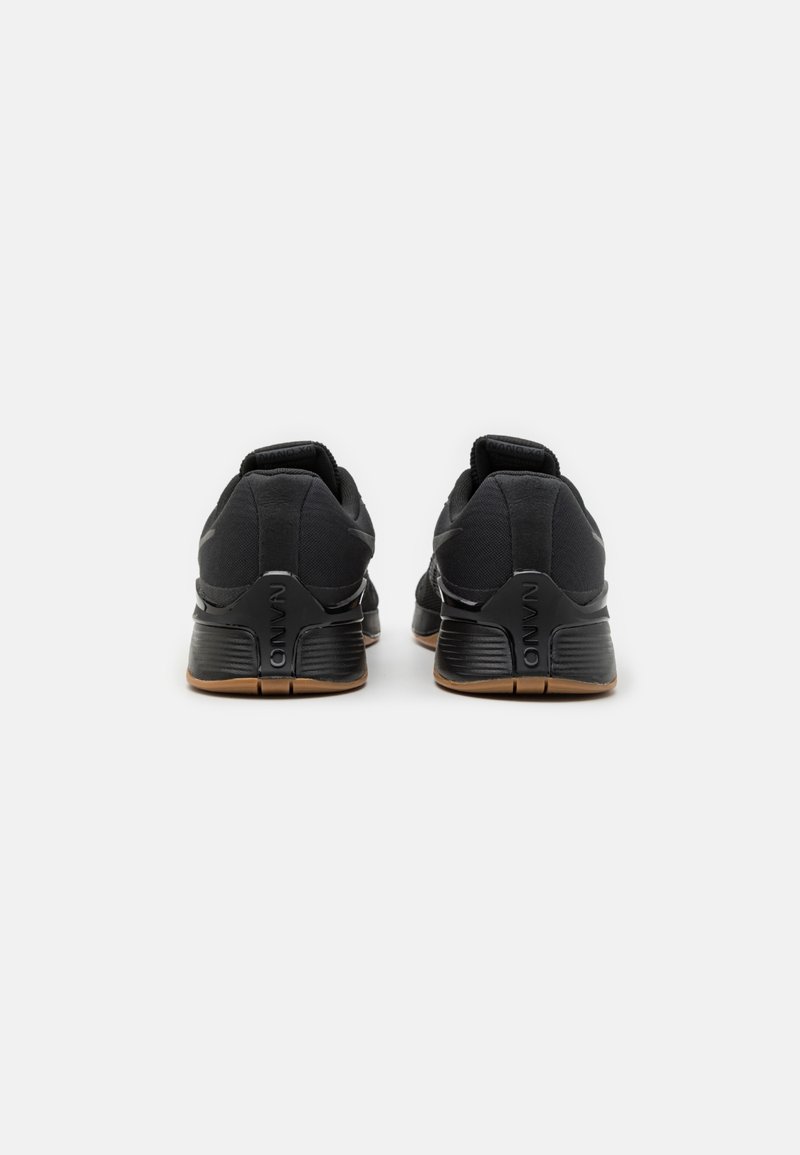 Chaussures de sport noires avec un dessus en tissu lisse, semelle en caoutchouc et un logo discret sur le talon. Comprend un col rembourré pour le confort.