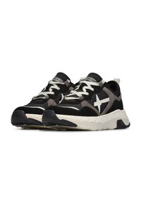 Sneaker nere e grigie con una tomaia testurizzata, lacci chiari e un logo a forma di stella bianca sul lato. Suola in gomma con motivo di battistrada.
