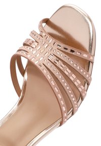 Sandalo con tacco alto a strisce di colore rosa chiaro con accenti metallici e decorazioni in strass; texture liscia e lucida e design con punta aperta.